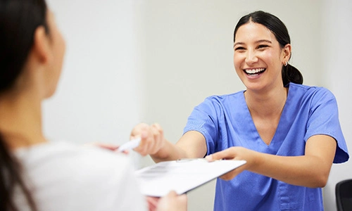 a dental assistant handing a patient forms