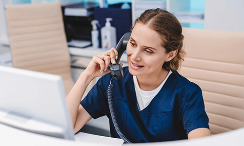 a front desk dental worker on the phone with a patient