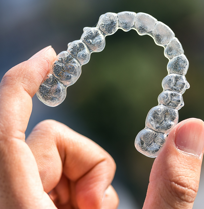 Close up of a hand holding a clear aligner
