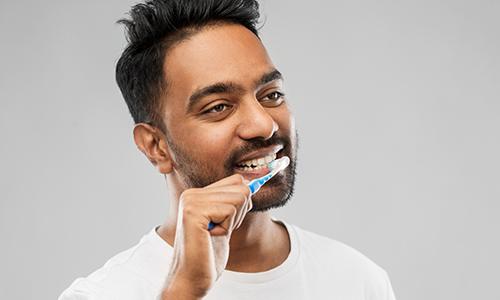 Young man in white t-shirt brushing his teeth
