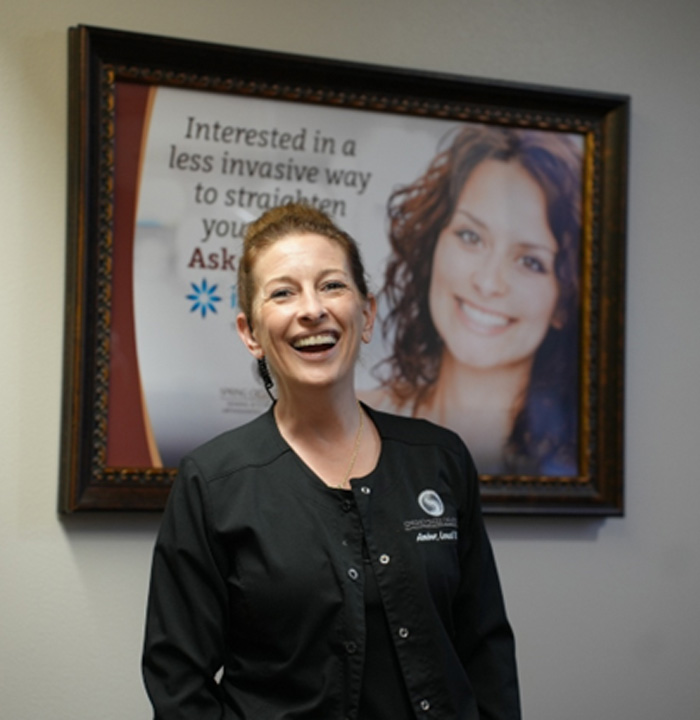 Team member at Spring Creek Dentistry in front of Invisalign sign