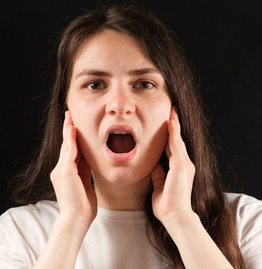 Woman sitting at her computer, struggling with a headache