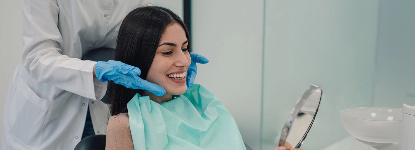Dental patient using hand mirror to admire her smile