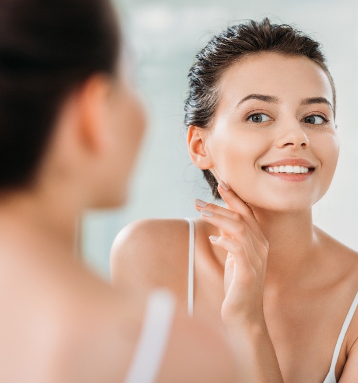 Young woman smiling at herself in bathroom mirror