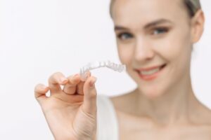 Smiling woman holding a clear aligner