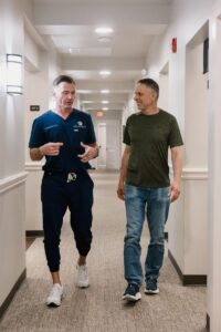 Dr. Oakley and patient walking through hallway, conversing 